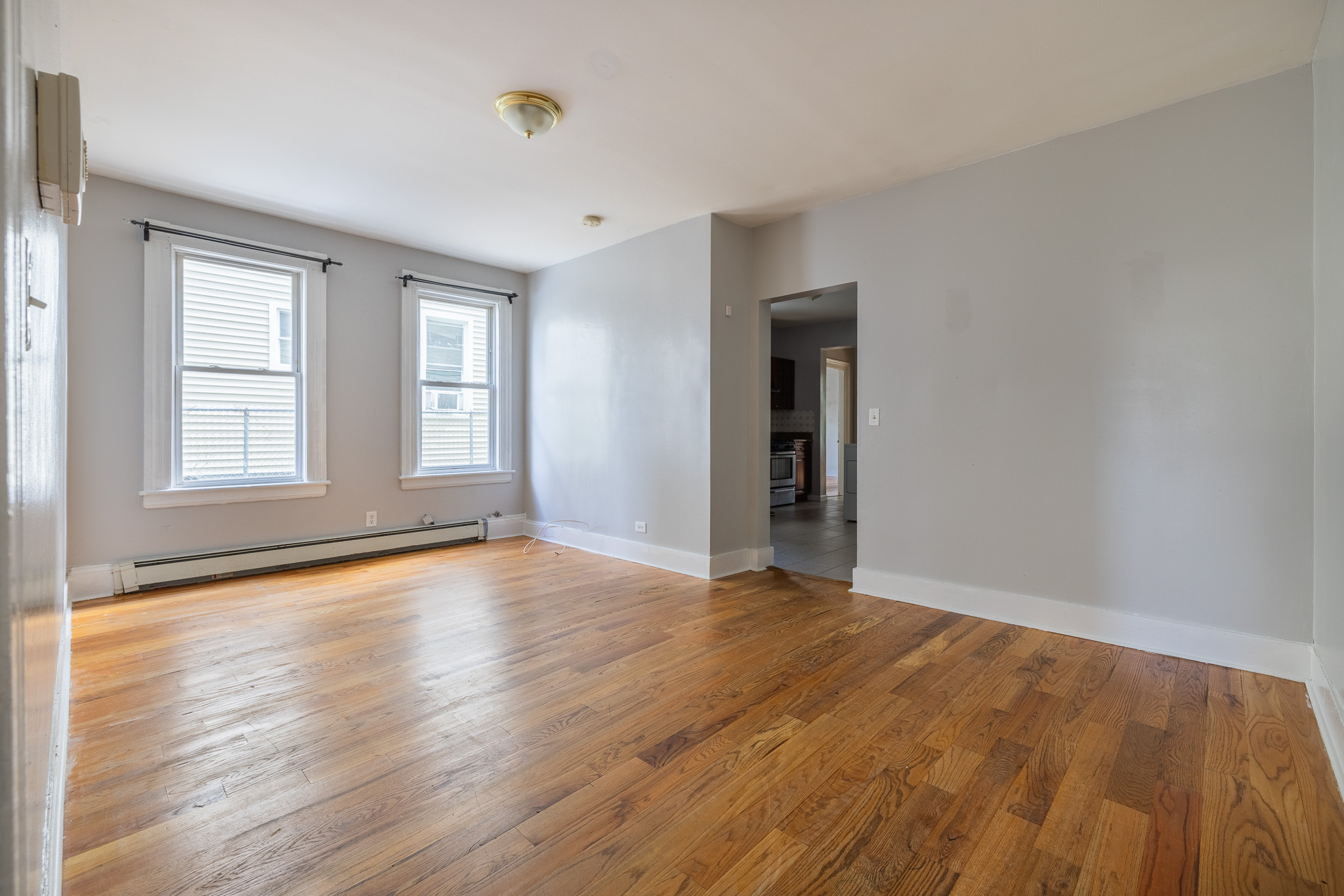 a view of an empty room with wooden floor and window