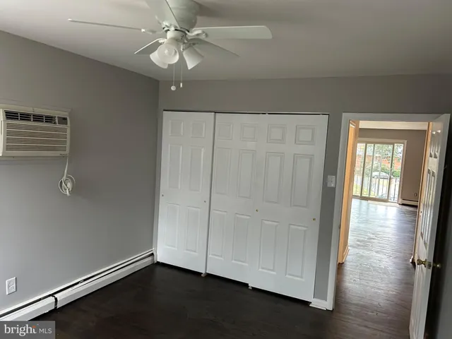 an empty room with wooden floor cabinet and windows