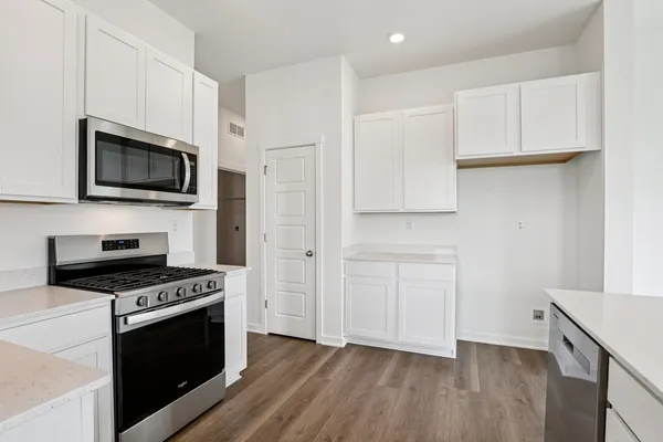 a kitchen with white cabinets stainless steel appliances and wooden floor