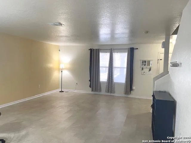 an empty room with windows and fireplace