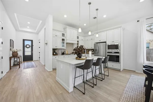 a kitchen with stainless steel appliances kitchen island granite countertop a refrigerator a stove a sink dishwasher and a dining table with wooden floor