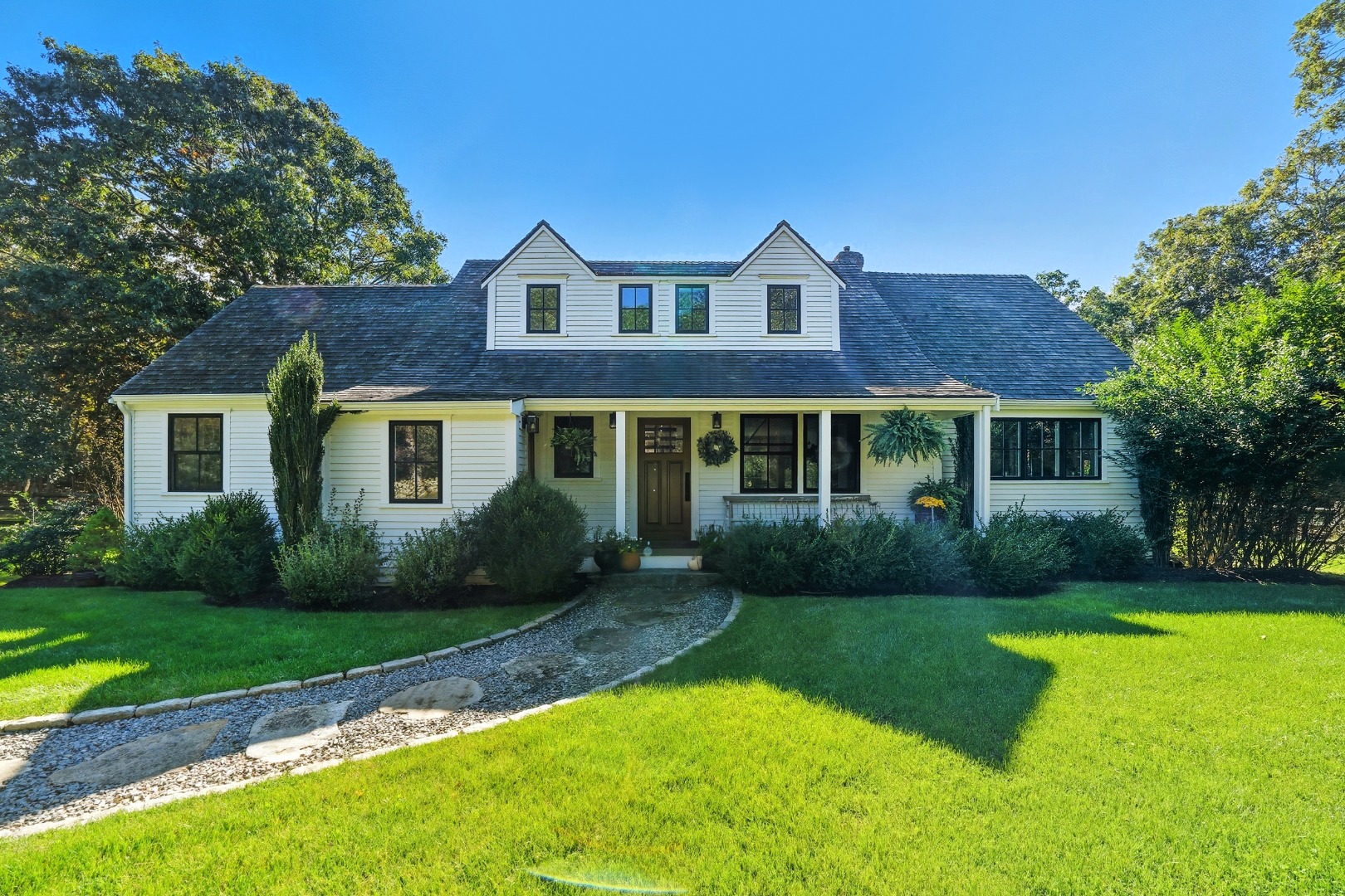 a view of a brick house with a yard plants and a large tree