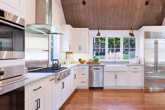 a kitchen with stainless steel appliances a sink a stove and white cabinets next to a window
