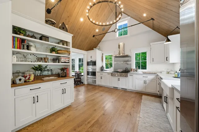 a large white kitchen with lots of counter space and wooden floor