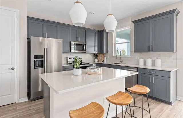 a kitchen with stainless steel appliances granite countertop a sink a stove a refrigerator cabinets a dining table and chairs