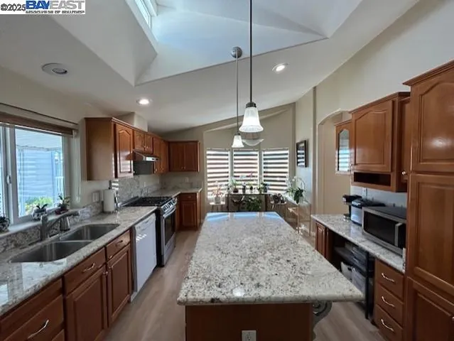 a kitchen with kitchen island granite countertop a sink stove and refrigerator