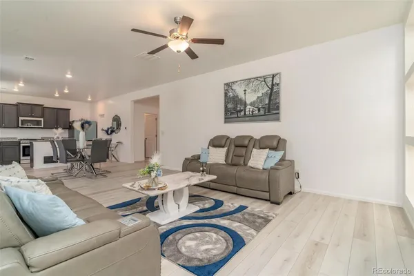a living room with furniture a clock and a ceiling fan