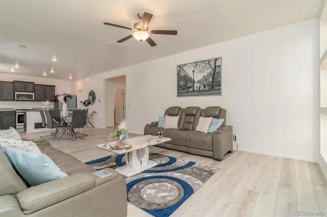 a living room with furniture a clock and a ceiling fan