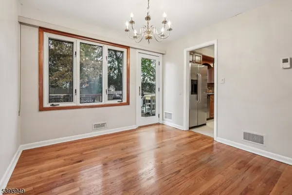 an empty room with wooden floor chandelier and windows