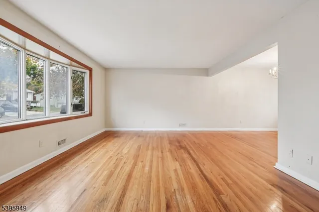 a view of an empty room with wooden floor and windows