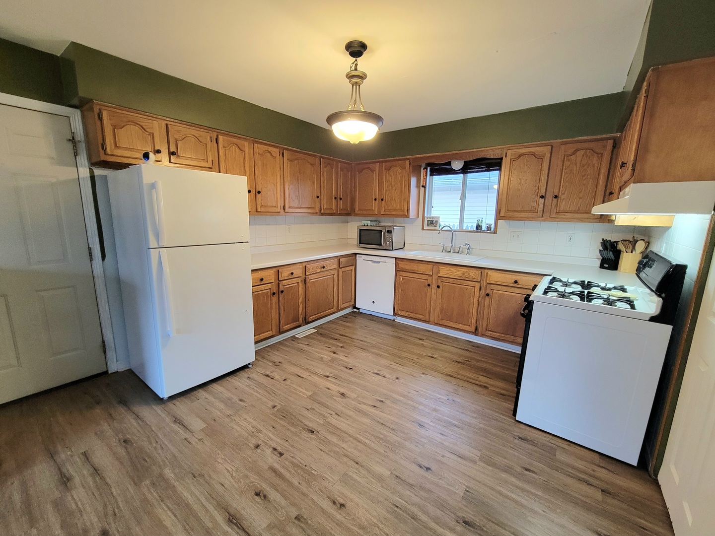 486 West Washington Street St. Anne, IL 60964 - Photo 6 of 14 a kitchen with wooden floors and white stainless steel appliances