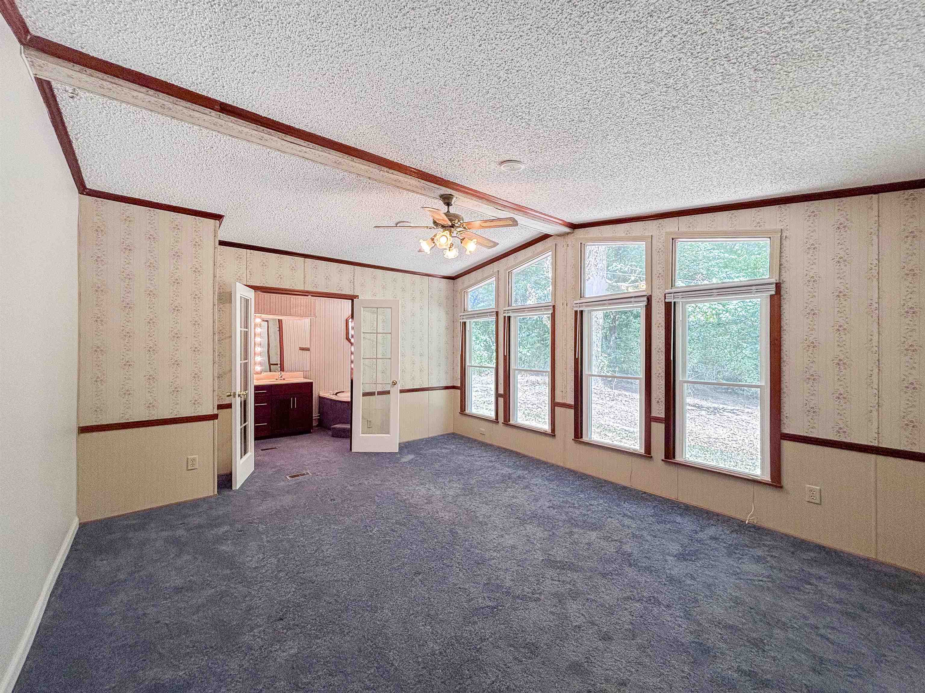 471 Milton Road Millington, TN 38053 - Photo 21 of 30 Expansive room featuring multiple trapezoidal and rectangular windows, a ceiling fan with integrated lighting, and a double French door entry to an adjacent space
