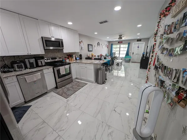 a kitchen with stainless steel appliances kitchen island granite countertop a sink a stove top oven and cabinets