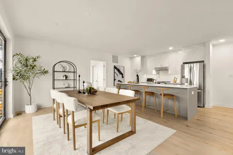 a open kitchen with stainless steel appliances granite countertop a table chairs sink and cabinets
