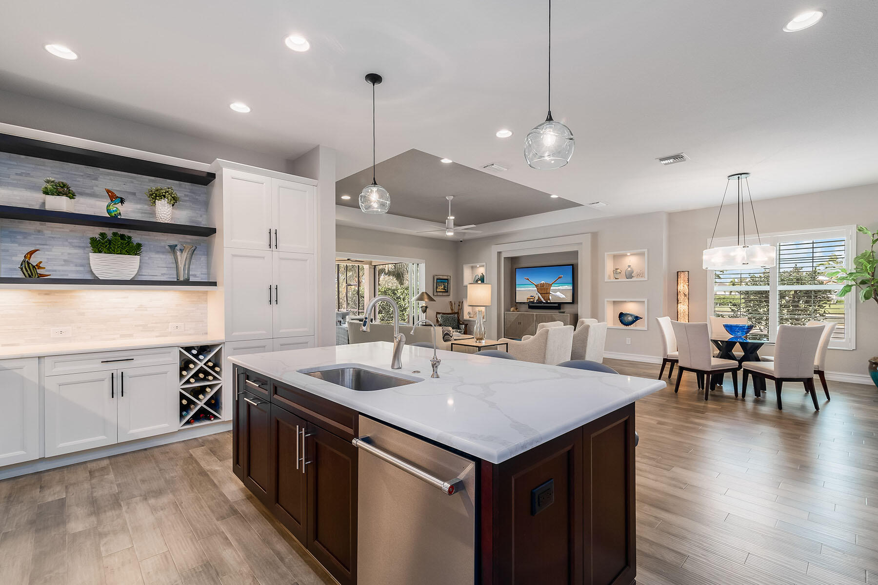 3192 Capistrano Lane Naples, FL 34114 - Photo 6 of 38 a kitchen with center island a sink dishwasher a stove and a dining table with wooden floor