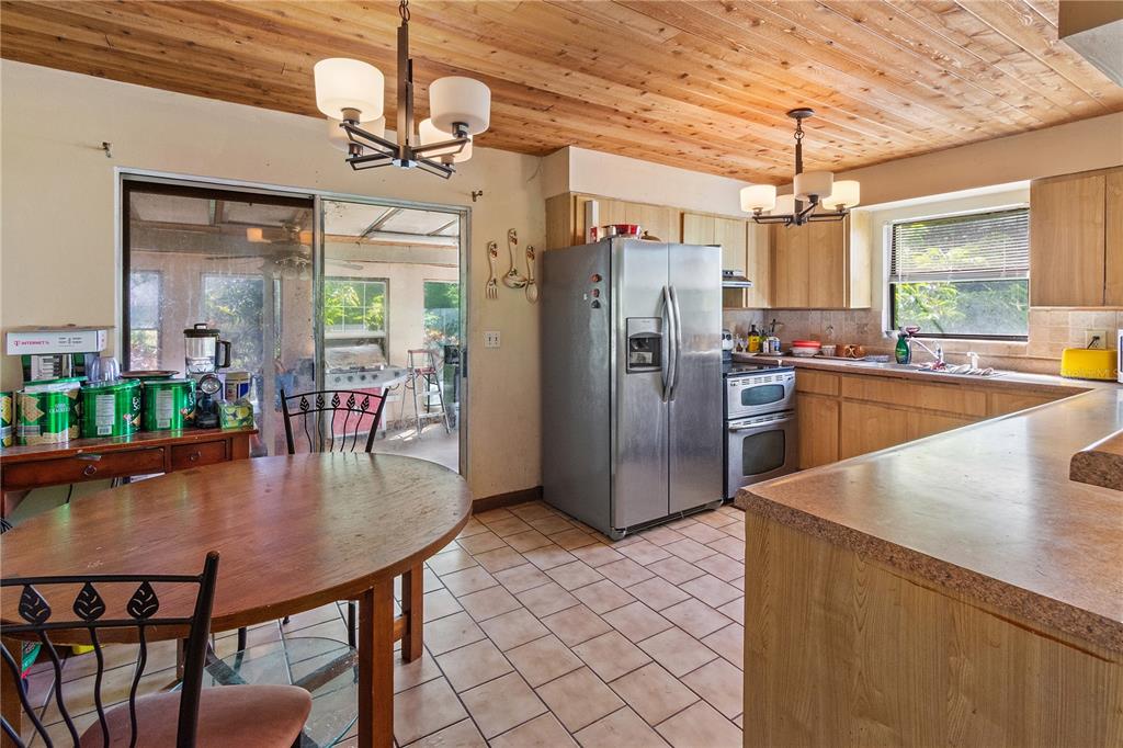 1360 Collany Lane Frostproof, FL 33843 - Photo 5 of 55 a kitchen with stainless steel appliances granite countertop a kitchen island a stove a dining table and chairs with wooden floor