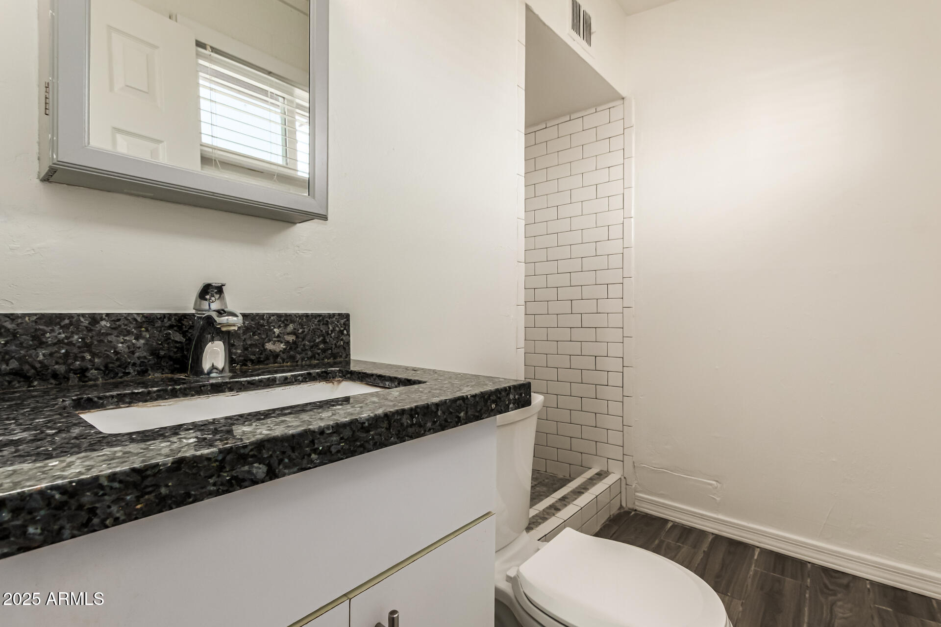 2150 West Missouri Avenue, Unit 108 Phoenix, AZ 85015 - Photo 13 of 28 a bathroom with a granite countertop toilet sink and mirror