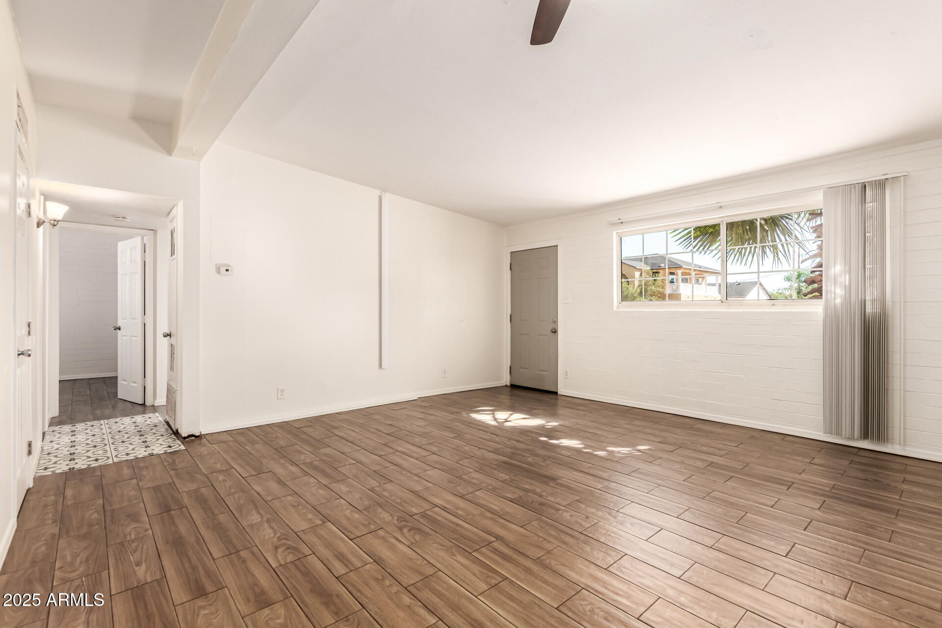 2150 West Missouri Avenue, Unit 108 Phoenix, AZ 85015 - Photo 5 of 28 a view of an empty room with wooden floor and a window