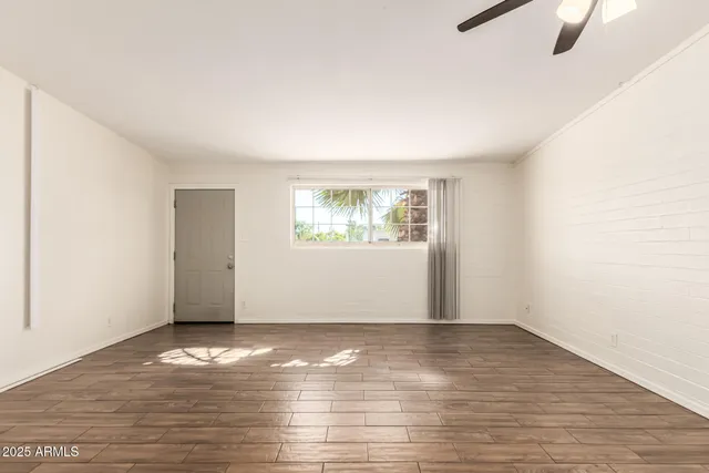 a view of an empty room with wooden floor and a window