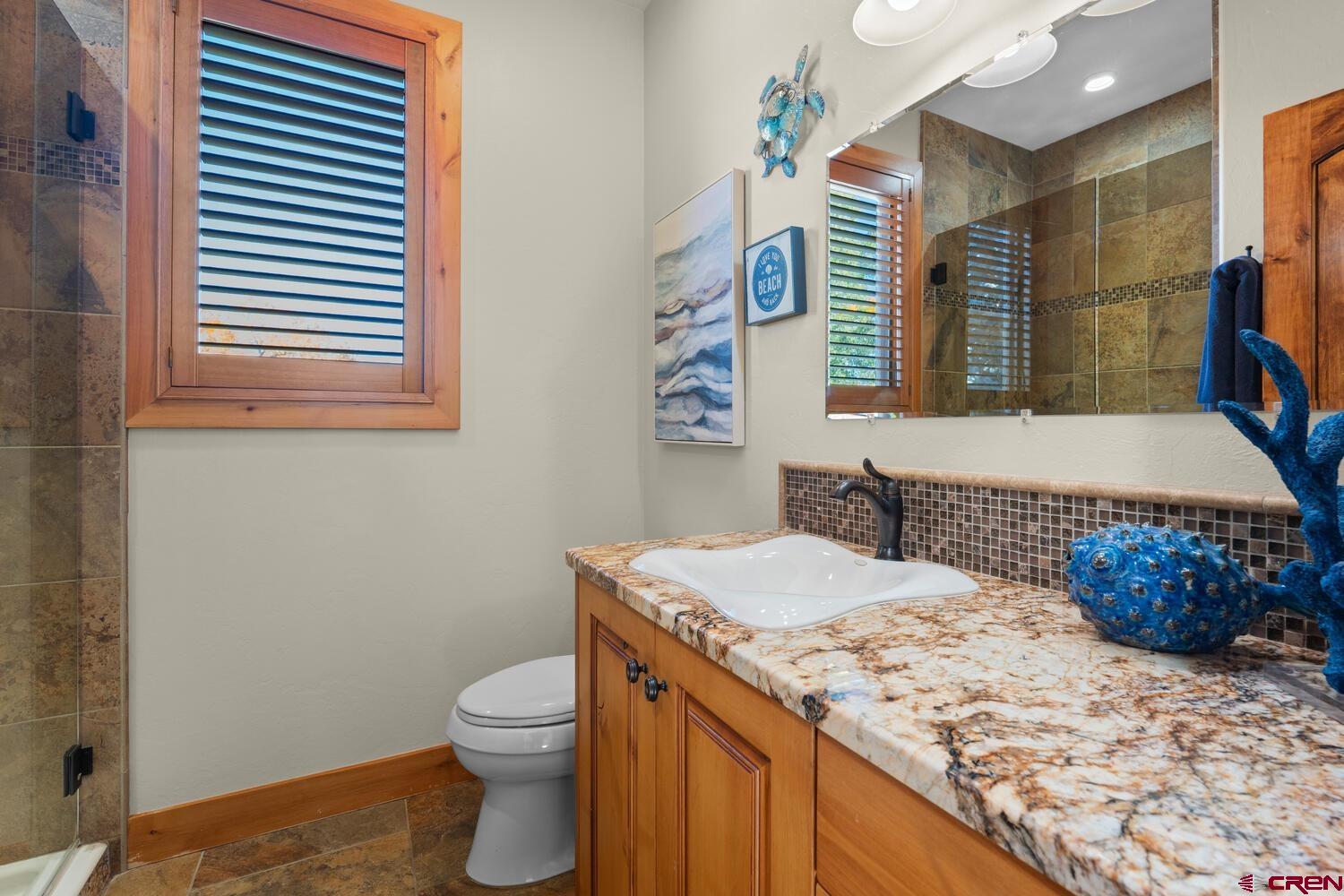 60075-60085 Oak Grove Road Montrose, CO 81403 - Photo 17 of 44 a bathroom with a granite countertop sink and a toilet