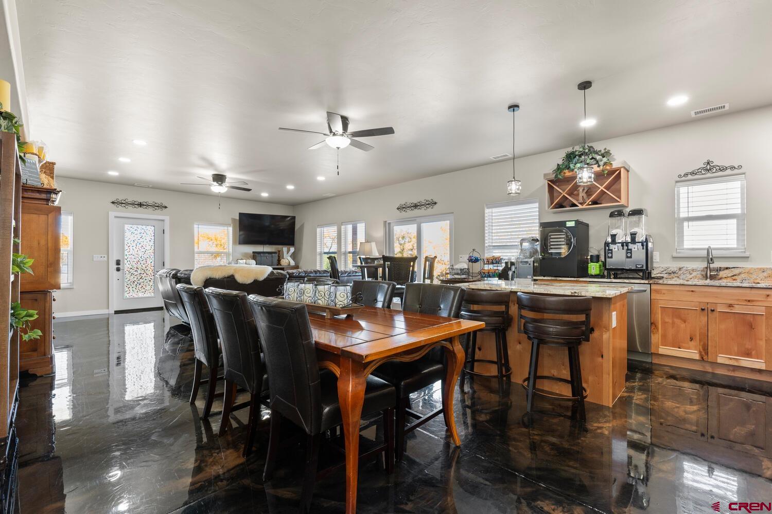 60075-60085 Oak Grove Road Montrose, CO 81403 - Photo 29 of 44 a kitchen with stainless steel appliances kitchen island granite countertop a table chairs and a refrigerator