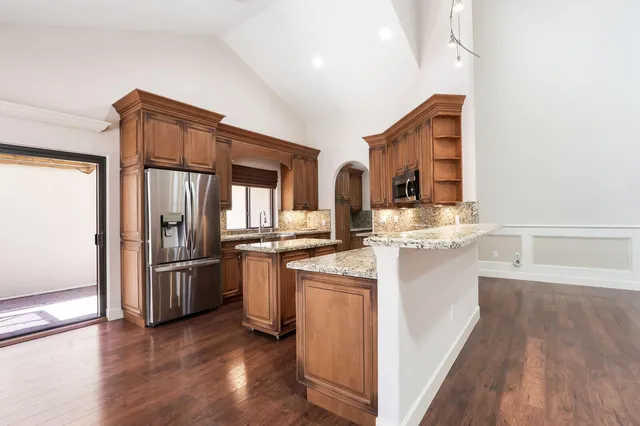 a kitchen with stainless steel appliances granite countertop a refrigerator a stove and a sink