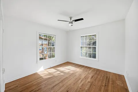 an empty room with wooden floor cabinet and windows