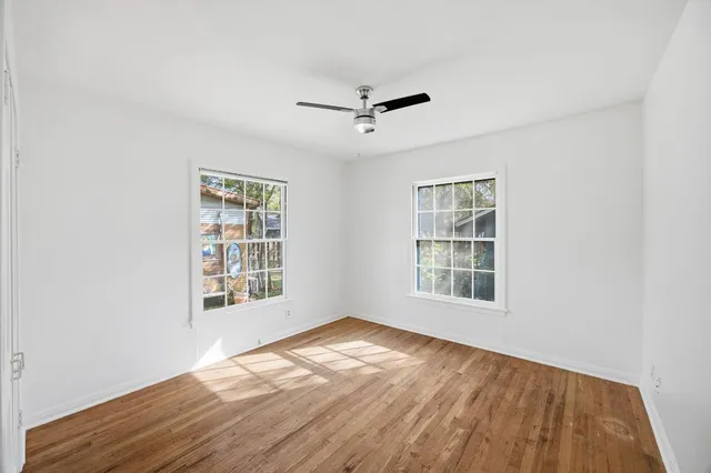 an empty room with wooden floor cabinet and windows