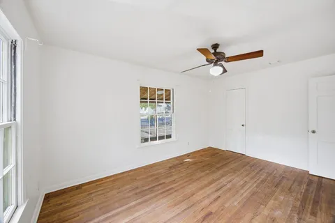 a view of empty room with wooden floor and fan