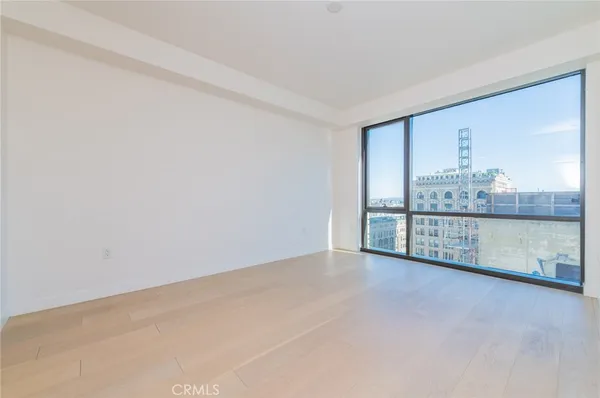 a kitchen with stainless steel appliances granite countertop a stove top oven a sink a refrigerator and white cabinets with wooden floor