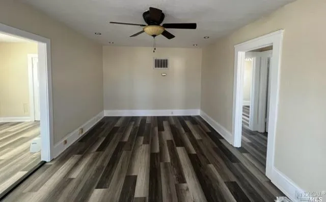 an empty room with wooden floor closet chandelier fan and windows