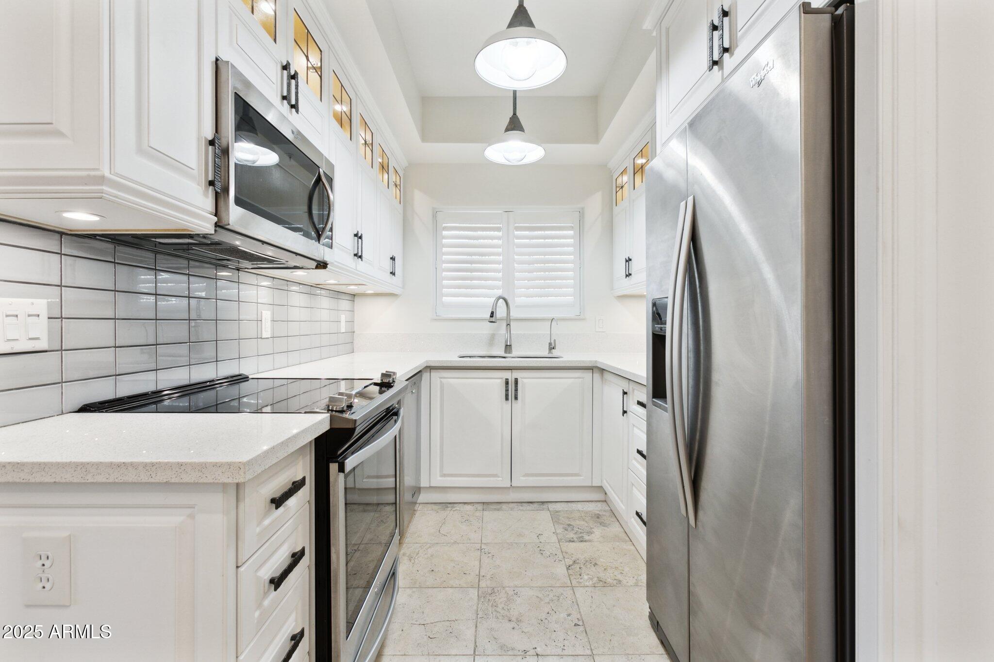 7710 East Gainey Ranch Road, Unit 229 Scottsdale, AZ 85258 - Photo 5 of 50 a kitchen with stainless steel appliances granite countertop a sink a stove a refrigerator a washer and dryer