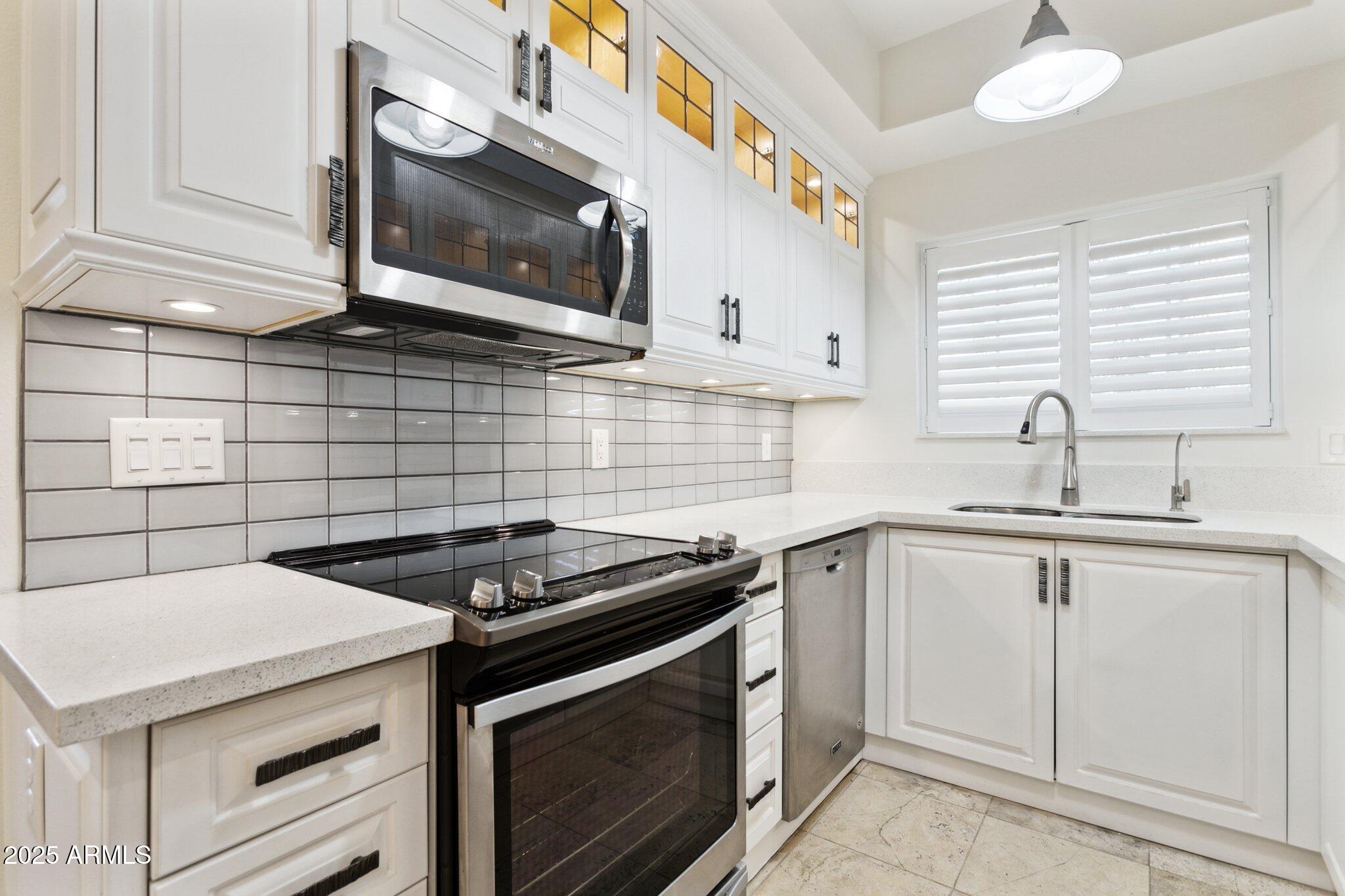 7710 East Gainey Ranch Road, Unit 229 Scottsdale, AZ 85258 - Photo 10 of 50 a kitchen with granite countertop white cabinets stainless steel appliances and a sink