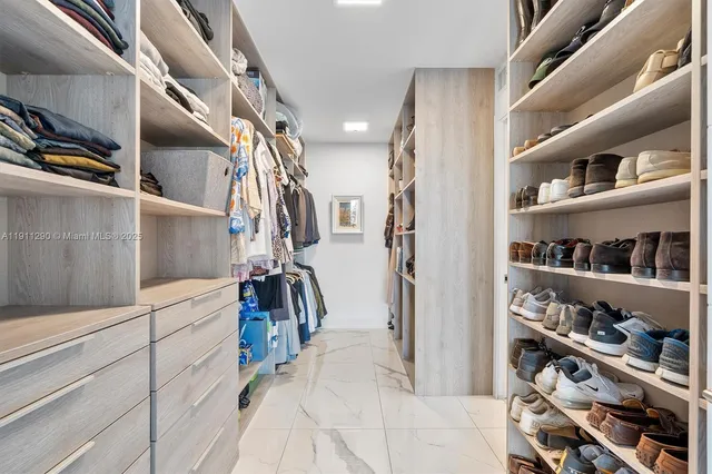 a view of walk in closet with clothes and shoes