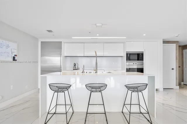 a kitchen with stainless steel appliances a table and chairs in it