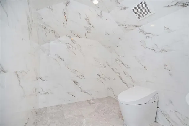 a white toilet sitting next to a white wall