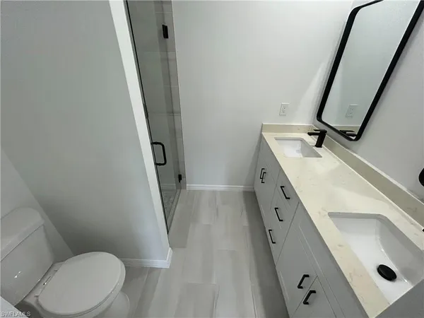 a bathroom with a sink a toilet a mirror and shower