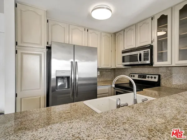 a kitchen with granite countertop a refrigerator and a sink