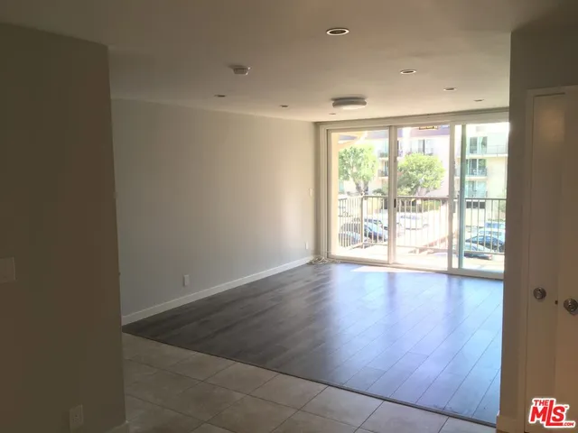 an empty room with wooden floor and windows with curtains