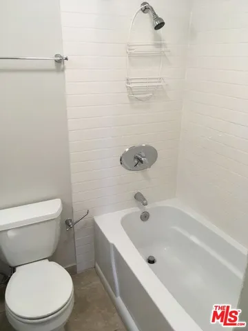 a white toilet sitting next to a bath tub