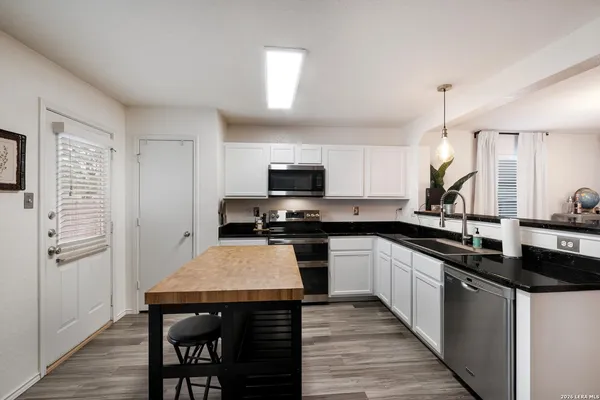 a kitchen with stainless steel appliances granite countertop a stove top oven a sink dishwasher and a refrigerator