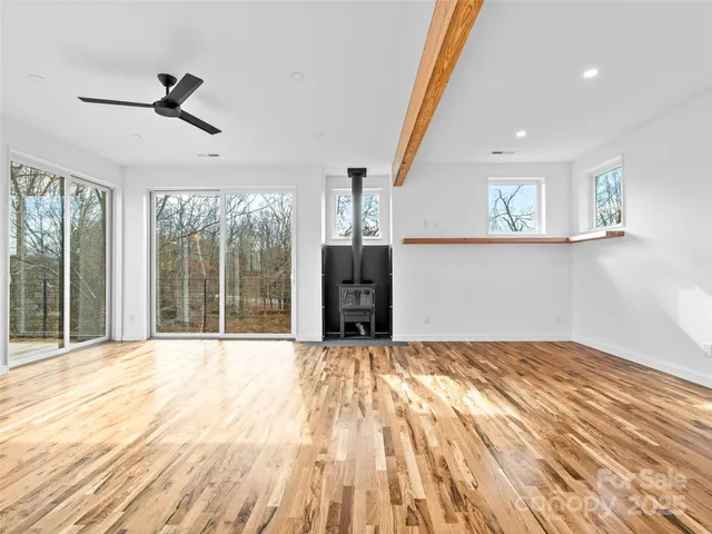 a view of an empty room with a window and a kitchen