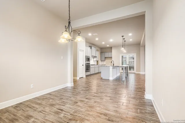 a view of a kitchen with a refrigerator a kitchen island white cabinetry and a stove