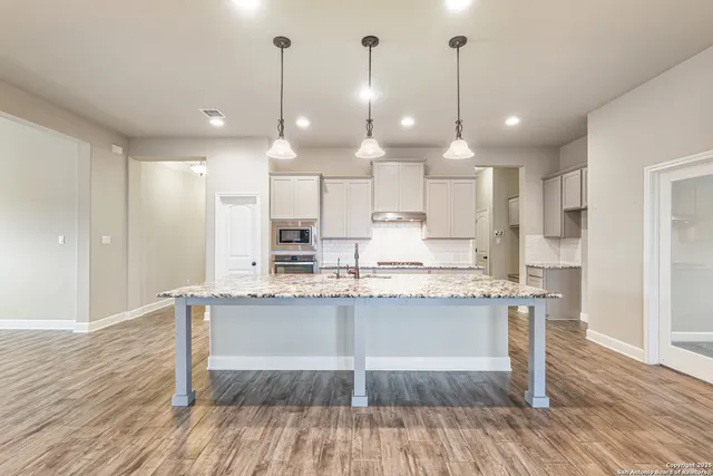 a kitchen with stainless steel appliances granite countertop wooden floors and white cabinets