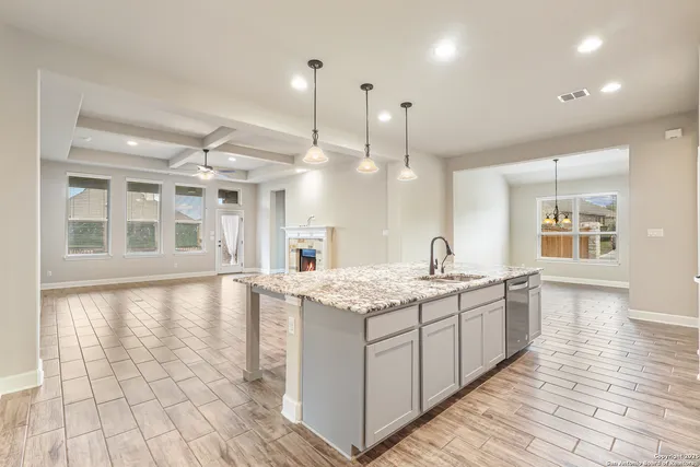 a large kitchen with stainless steel appliances kitchen island granite countertop a large counter top and a wooden floors