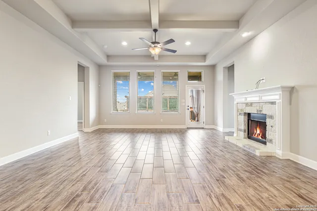 a view of an empty room with wooden floor fireplace and a window