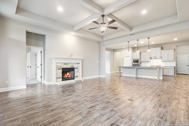 a view of an empty room with wooden floor fireplace and a window