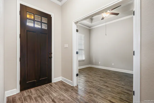 a view of an empty room with wooden floor and a window