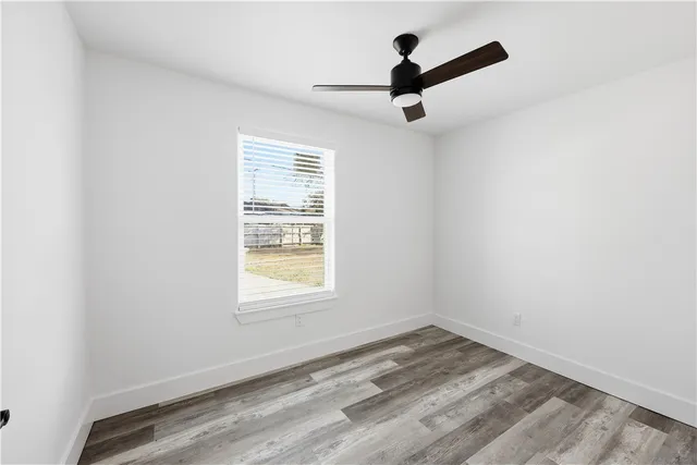 an empty room with a ceiling fan and window