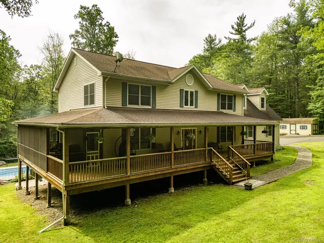 a view of a house with a wooden deck and a big yard